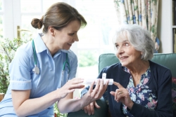 caregiver advising elderly woman on taking medication